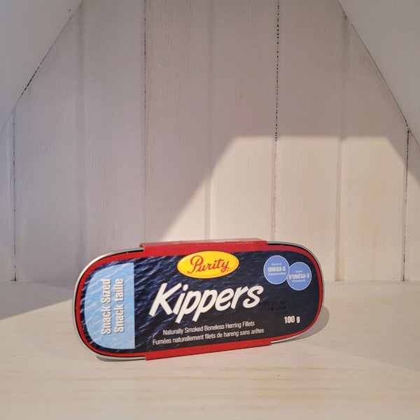 100g tin of Kippers from Purity on a wooden surface with a white wall background