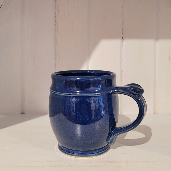Blue ceramic mug on a wooden surface with a white wall background