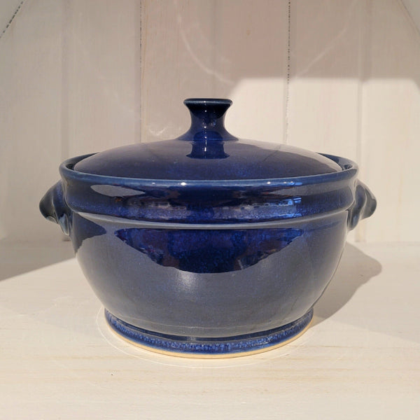 Blue ceramic casserole dish with lid on a white surface