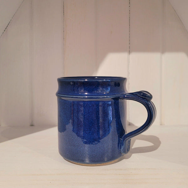 Blue ceramic mug on a white surface with a neutral background