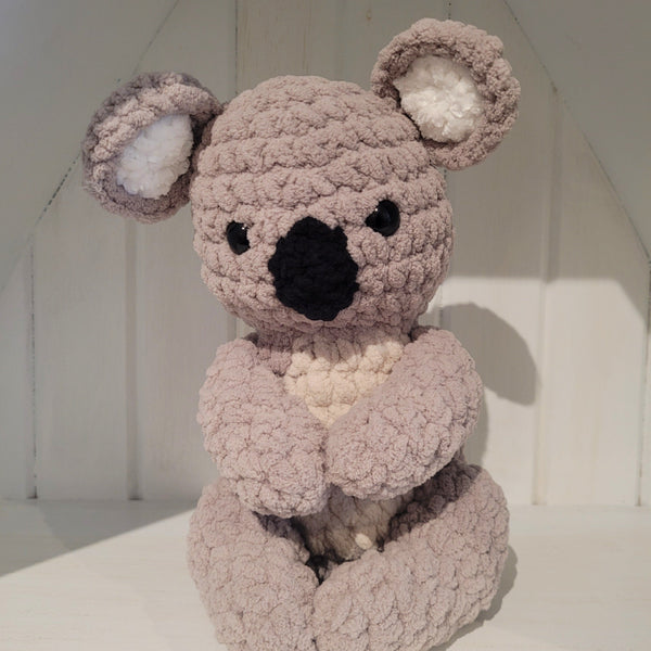 crochet koala on a shelf with white background
