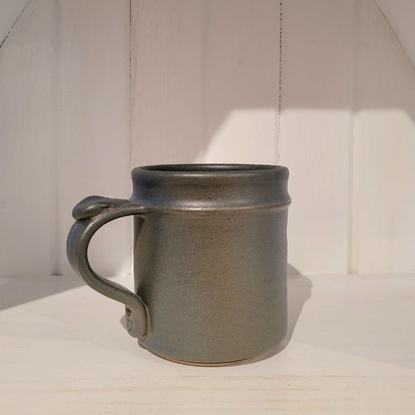 Gray ceramic mug on a white surface with a neutral background