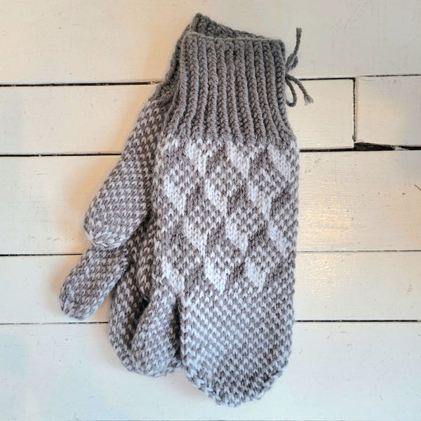Pair of gray knitted trigger mittens on a wooden surface