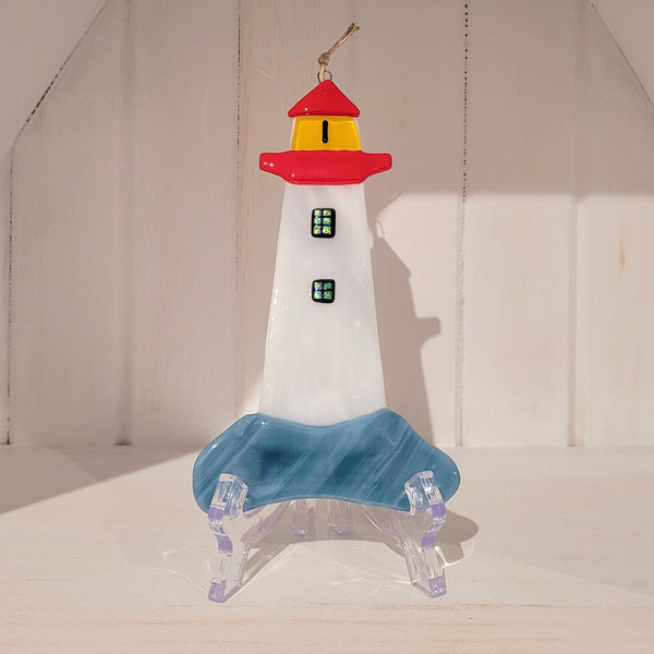 Colorful fused glass lighthouse ornament on a white background