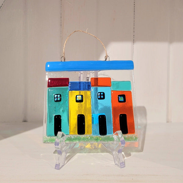 Colorful fused glass rowhouses hanging decoration suncatcher on a white background