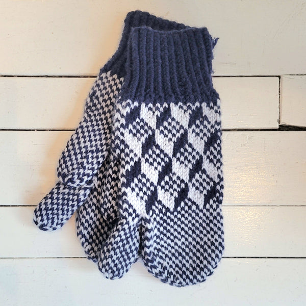 Pair of blue and white patterned trigger mittens on a wooden surface