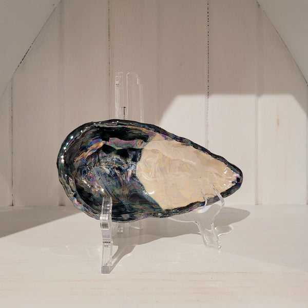 Small blue mussel shell ceramic dish on a stand against a neutral background