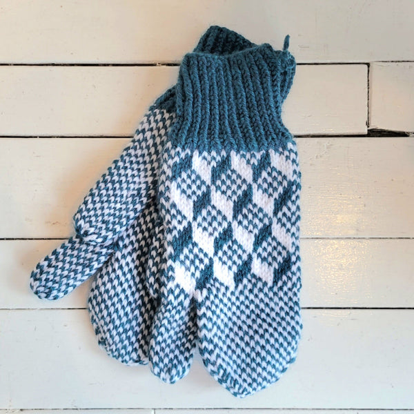 Pair of teal and white patterned trigger mittens on a wooden surface