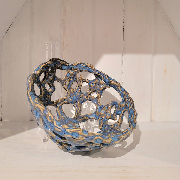 Blue and gold ceramic bowl with a textured surface on a white background