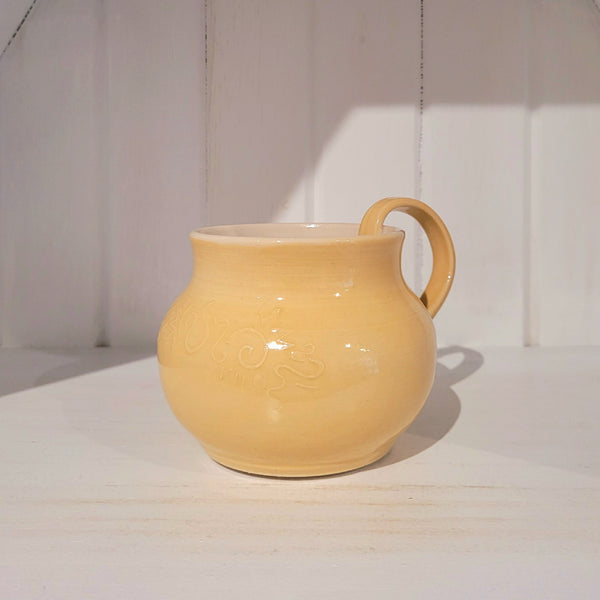 Yellow ceramic mug with geometric design on a white surface