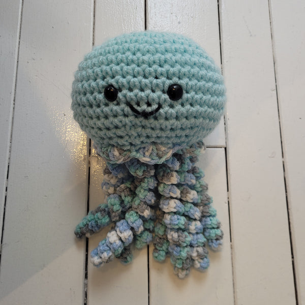 blue crochet plush toy jellyfish with smiley face and colourful tentacles on a white background