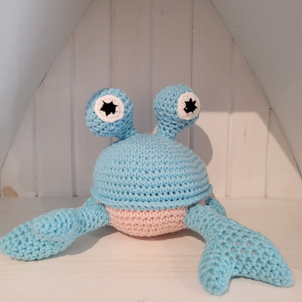 Crocheted blue crab stuffed toy on a white surface with a neutral background