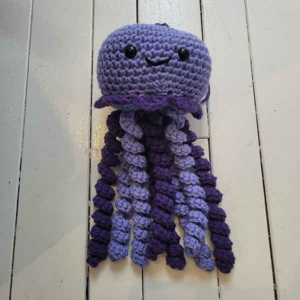 purple crochet plush toy jellyfish with smiley face and colourful tentacles on a white background