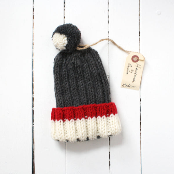 Medium grey toque with red and white brim and tassel