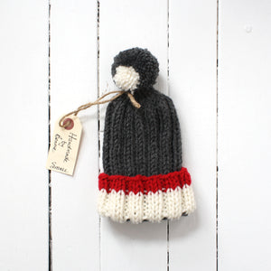 Small grey toque with white and red brim and tassel